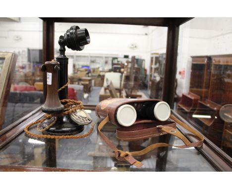 A candlestick telephone and a cased pair of binoculars.