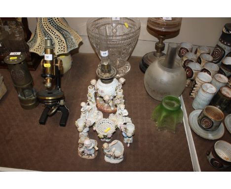 A Dresden porcelain oil lamp with cherub decoration; a pair of similar candlestick bases and other porcelain ornaments 
