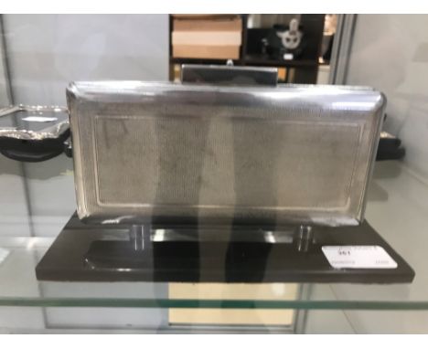 A retro chrome cigarette case on a black marble stand