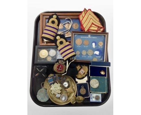 A group of military decorations, including rank chevrons, epaulettes, together with framed coin sets, paperweight, Festival o