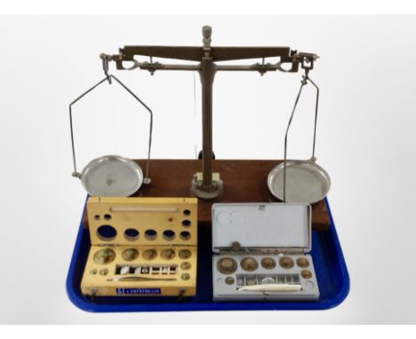 A set of scales on mahogany plinth and two sets of weights in boxes.