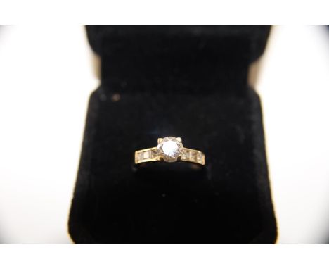 An 18ct gold white stone solitaire ring with accents to the shoulders 