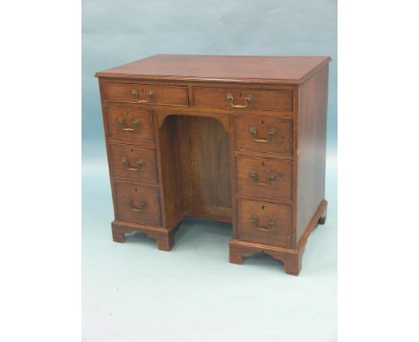 A George III mahogany kneehole desk, arrangement of eight drawers and central cupboard, brass swan-neck handles, bracket feet