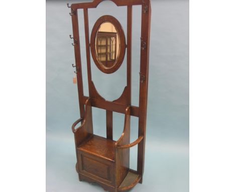 A solid, dark oak hall stand, features include oval mirror, six coat-hooks, stick-stands with drip-trays, 6ft. high