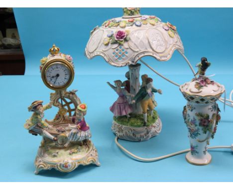 A porcelain figural table lamp, with flower-encrusted shade, 15in., together with a similar timepiece, and a flower-encrusted