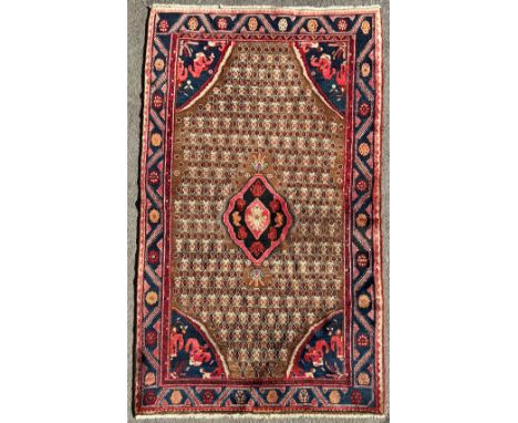 An Iranian hand knotted Koliai Songhur wool rug, central blue and red medallion, within cream lattice field, triple layer bor