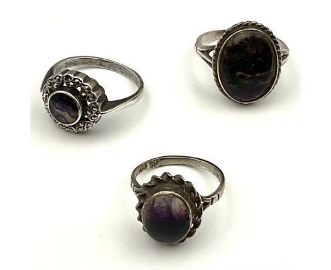 Three Silver Blue John Rings; to include an approx. 14mm x 10mm oval cabochon blue john ring with a domed glass top to protec