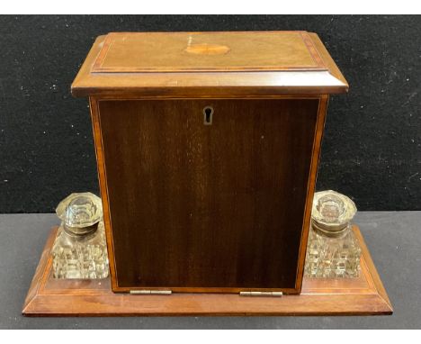 An Edwardian crossbanded mahogany fall-front desktop stationery cabinet, the hinged cover with batwing patera, enclosing an a