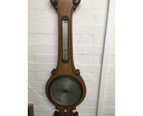 A Negretti and Zambia oak barometer with applied thermometer and silver dial . 108 cm .