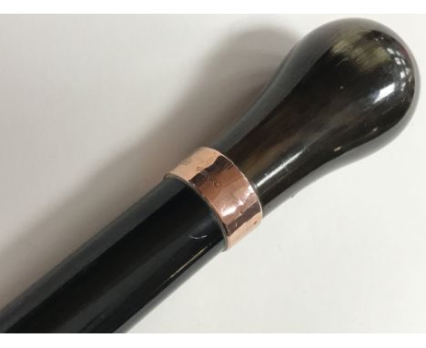 An ebonized walking stick with horn handle and 9ct gold collar