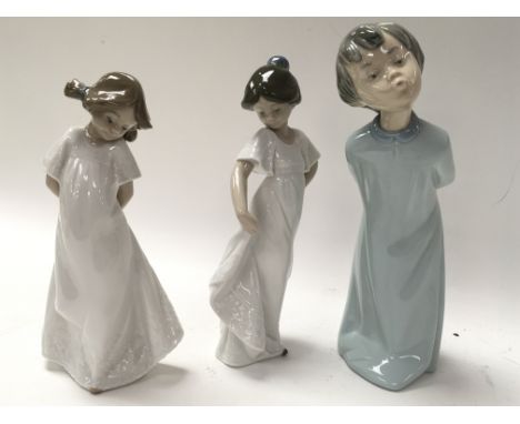 Three Nao by Lladro figures from the collection Bed Time. Two young girls in white night dresses and one boy In a long blue n