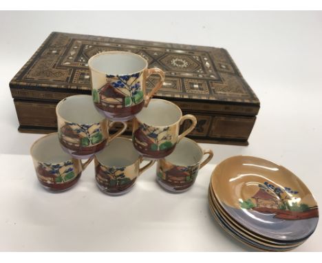 A inlaid parquetry is with mother of pearl inlays. Inside, this box contains a miniature six piece Japanese tea set of cups a