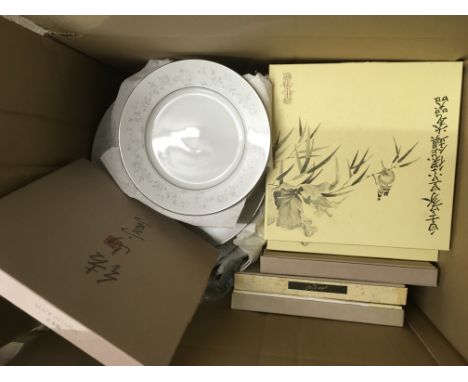 Three boxes containing a collection of boxed Japanese plates, a lamp, part tea set and other oddments.