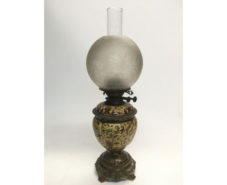 A Victorian oil lamp with a ceramic reservoir decorated with flowers on a yellow ground, the shade with etched decoration of 