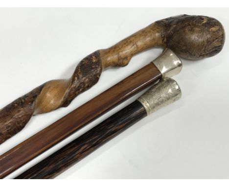 Two walking canes with silver tops and one other rustic walking stick