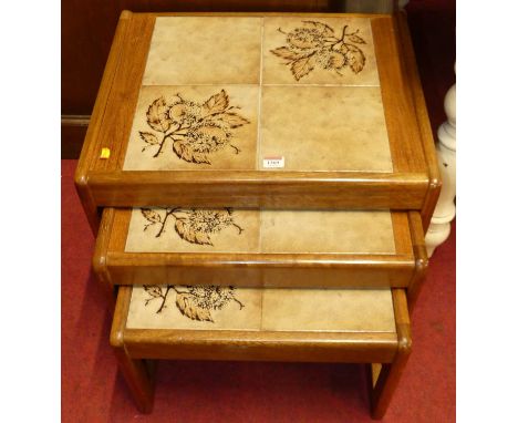 A 1970s teak and tile inset nest of three occasional tables, the largest width 54cm 