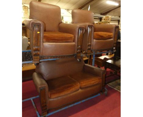 A 1920s oak and rexine upholstered three-piece suite, the sofa being a two-seater, each with showframe, and on castors, sofa 