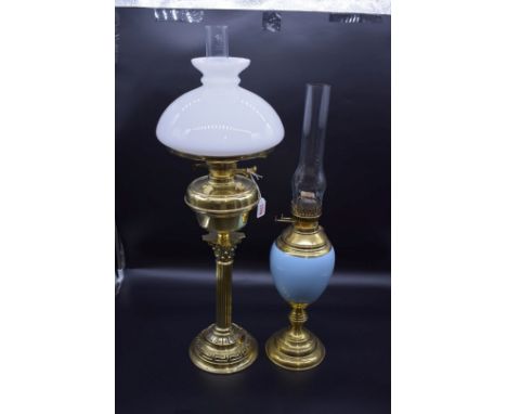 An antique brass Corinthian column oil lamp, with opaque glass shade, height including chimney 76cm; together with another br