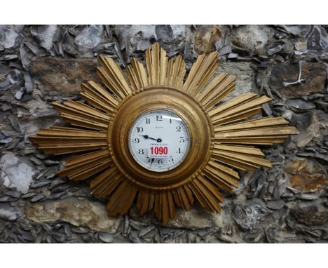 A gilt sunburst wall timepiece,&nbsp;with enamel dial, 44.5cm wide.&nbsp; 