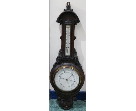 Late Victorian aneroid barometer with thermometer in carved oak case.