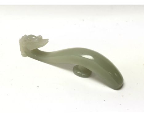 A carved green jade belt hook.