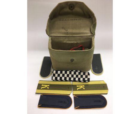 A green canvas military bag and contents including epaulettes and sewing materials.