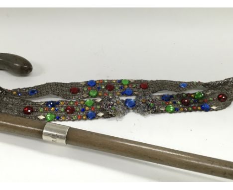 A silver collared wooden walking stick and an elaborate filigree belt.