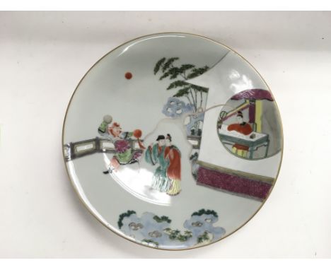 A Chinese plate painted with various figures in a garden setting, approx diameter 26.5cm.