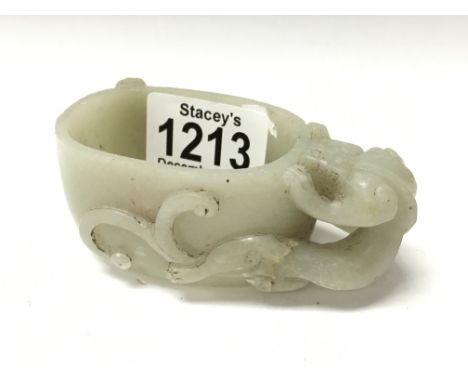 A Chinese carved jade libation cut with the handle in the form of a figural lion.