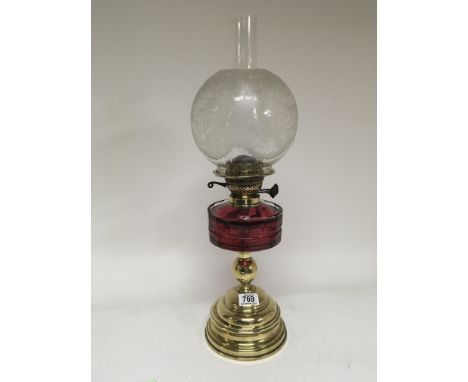 A Quality Victorian oil lamp with a cranberry glass reservoir brass column and acid etched shade. 58cm