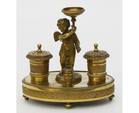 Figürliche Empireschreibtischgarnitur. Feuervergoldete Bronze. Ovaler Sockel auf vier Füßen, darauf stehender Amor, flankiert