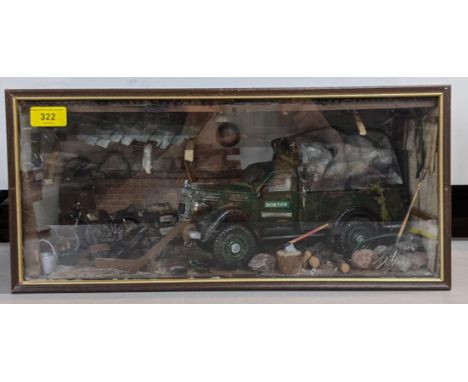 A model garage scene in a glazed case depicting a Norton truck surrounded by tools and equipment in a tumbled down garageLoca