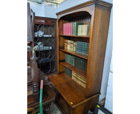 A good quality oak bookcase, shaped cornice with arched apron four open shelves, above a base with twin cupboard panelled doo