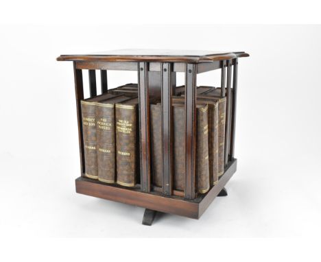 An Edwardian mahogany table top revolving bookcase, with serpentine moulded edge and inlaid with stringing and central floral