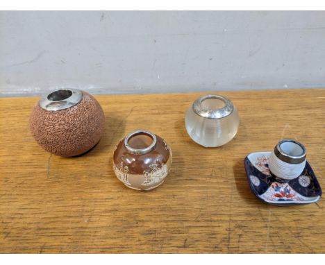 A group of four ceramic and glass match strikers with silver rims to include a machine threaded glass example, and two Doulto