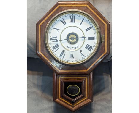 A vintage American Wall Clock by Seth Thomas having a white enamel dial with Roman numerals, in a multi-sided mahogany and in