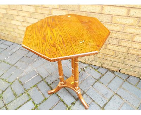 An octagonal topped oak table on tripod support 