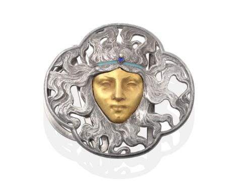 An Art Nouveau Belt Buckle, by Lalique, as a female face within an oxydized pierced quatrefoil frame as billowing hair, with 
