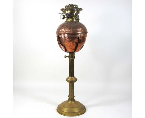 An American Arts and Crafts adjustable brass and copper oil lamp, by Benziger, New York, having a hammered reservoir and Hink
