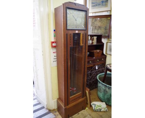 An Art Deco ebonized and oak eight day chiming longcase clock, having 12 x 9in silvered dial, with three weights, pendulum, a