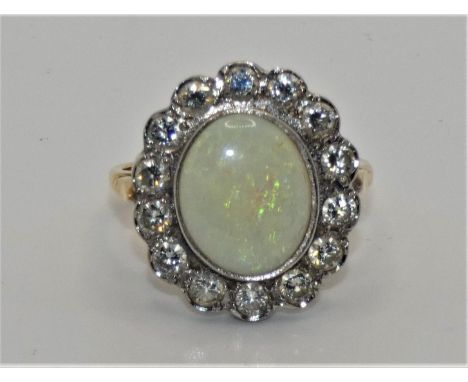 An 18ct gold opal and diamond cluster ring, collet set with an oval stone, 12 x 10 mm, bordered by 14 brilliant cuts, total w