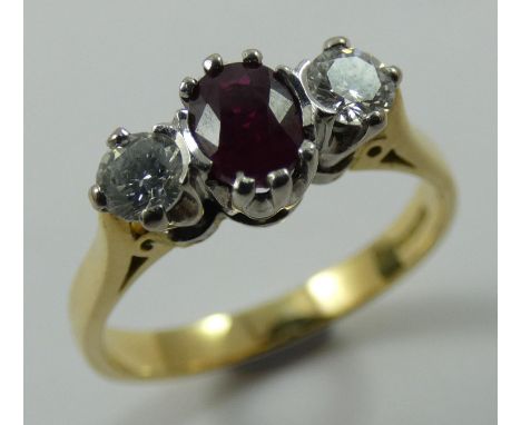 An 18ct gold ruby and diamond three stone ring, claw set with an oval mixed cut stone flanked by brilliants, approximately 0.