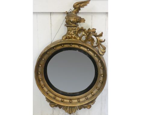 A giltwood convex circular wall mirror, with eagle and floral scroll surmount, A/F, 108 cm. 