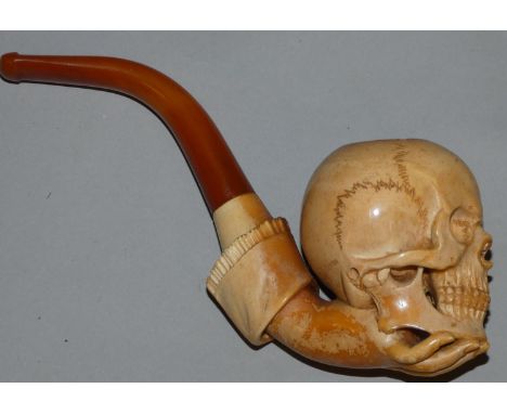 A Victorian meerschaum pipe, carved in the form of a skull held by a hand, 17 cm. 