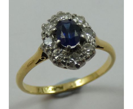 An 18ct gold sapphire and diamond cluster ring, claw set with an oval mixed cut stone, bordered by eight single cut stones, d