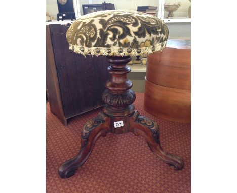 An early 20th century revolving piano stool with upholstered seat and carved tripod support.