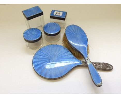 The residue of an art deco silver and enamel dressing table set comprising four lidded jars, mirror and brush (latter two wit