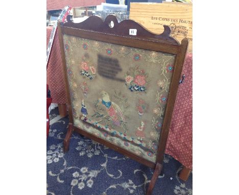 A glazed mahogany fire screen, inset with a mid 19th sampler, worked by Hester Garlick, decorated with a large parrot, two yo