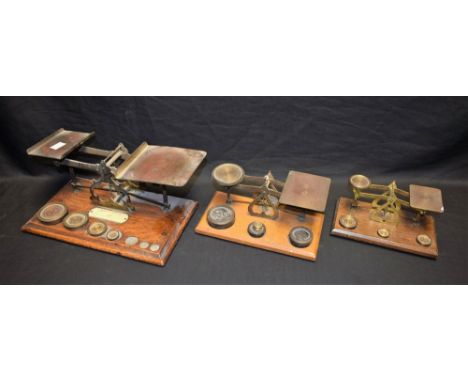 A set of brass postal scales, with weights, on an oak base; two others, similar (3)