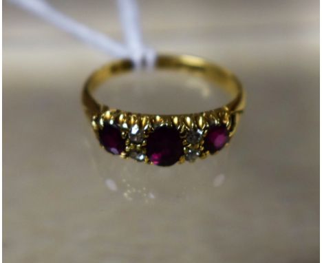 An Edwardian seven stone diamond and ruby line ring, three oval and round cut pinky red rubies, each divided by a pair of old